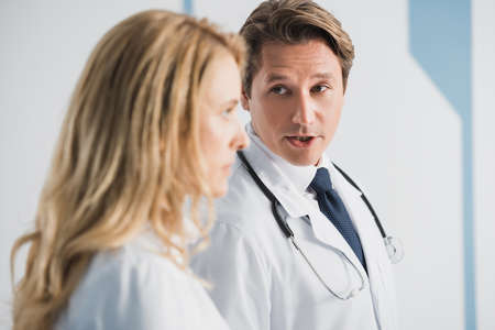 Selective focus of doctor looking at colleague while talking in clinic