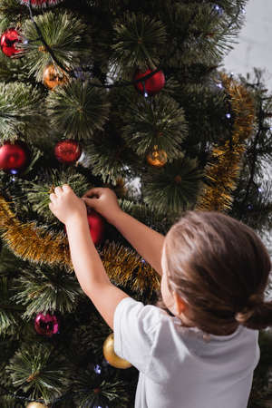 Back view of girl decorating christmas pine at homeの写真素材
