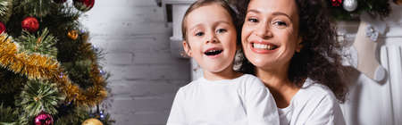 Panoramic shot of mother and daughter with open mouth looking at camera