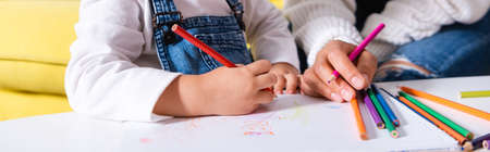 Panoramic shot of daughter and mother drawing with color pencilsの写真素材
