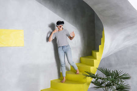 Excited woman in vr header standing on stairs at home