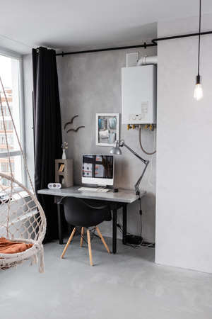 Spacious workplace interior with computer and hanging chair