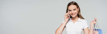 panoramic crop of joyful woman talking on smartphone isolated on grayの写真素材