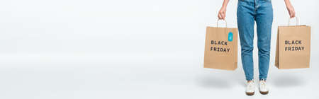 customer holding shopping bags with sale tag and black friday lettering isolated on white, panoramic...