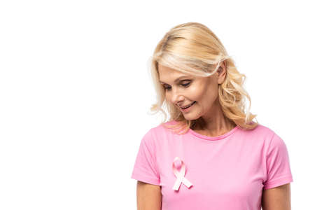 Blonde woman looking at pink ribbon of breast cancer awareness isolated on whiteの写真素材