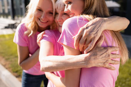 Selective focus of women in pink t-shirts hugging, concept of breast cancerの写真素材