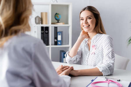 Selective focus of young adult woman sitting and holding hand with doctorの写真素材