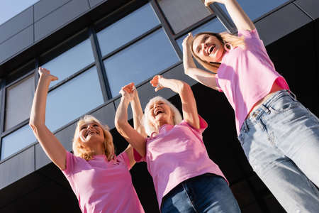 Low angle view of women with hands in air outdoors, concept of breast cancerの写真素材