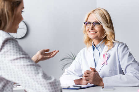 Selective focus of doctor with clenched hands sitting near patient at workplaceの写真素材