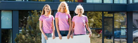Panoramic shot of women holding blank placard with building on backgroundの写真素材
