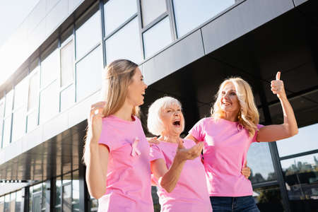 Three women hugging and laughing outdoors, concept of breast cancerの写真素材