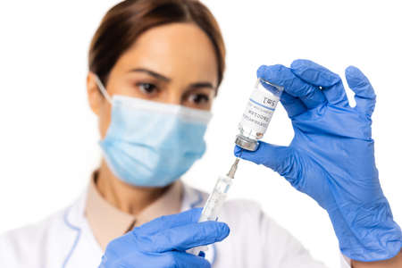 Selective focus of doctor in latex gloves picking up coronavirus vaccine in syringe isolated on...