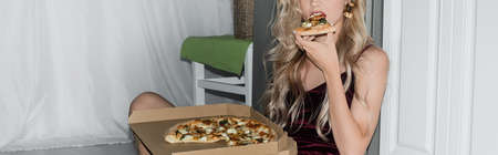 cropped view of young blonde woman eating pizza, horizontal image