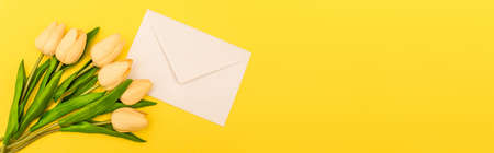 top view of envelope near tulips on yellow background, panoramic shotの写真素材