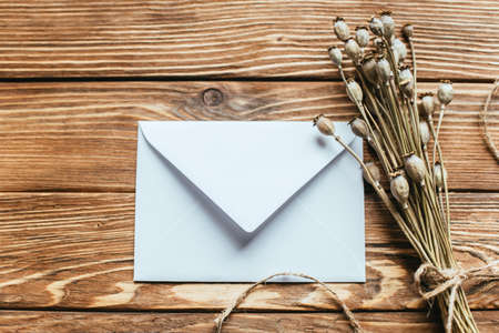 top view of envelope near dry poppies on wooden backgroundの写真素材