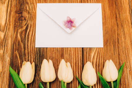 top view of envelope near tulips on wooden backgroundの写真素材