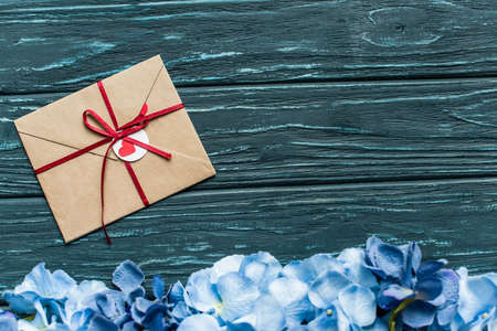 top view of wooden green background with blue floral border and envelope