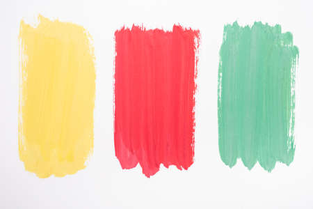 top view of abstract colorful green, yellow and red paint brushstrokes on white backgroundの写真素材