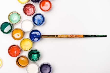 top view of Gouache paints and paintbrush on white background