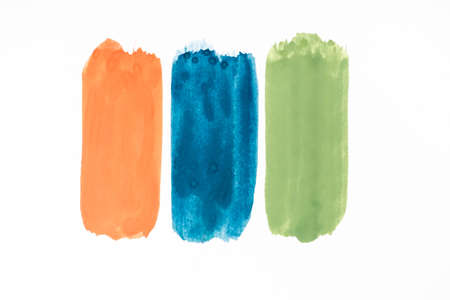 top view of abstract colorful green, orange and blue paint brushstrokes on white backgroundの写真素材