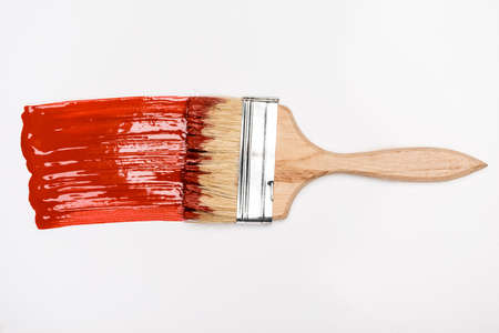 top view of paintbrush near colorful red paint brushstroke on white backgroundの写真素材