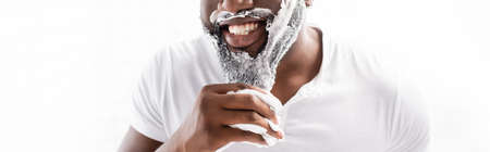 panoramic view of smiling afro-american man with shaving foam on face looking at cameraの写真素材