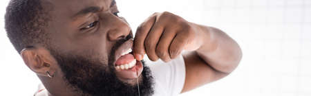 panoramic view of afro-american man using dental floss
