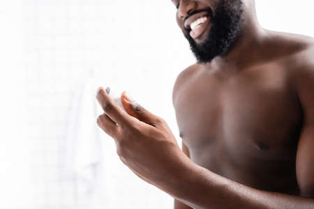 cropped view of smiling afro-american man holding deodorant in handの写真素材