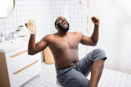 afro-american man tearing off wax strips and screaming from pain