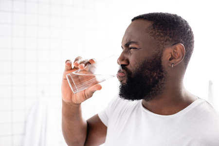 afro-american man grimacing and drinking waterの写真素材