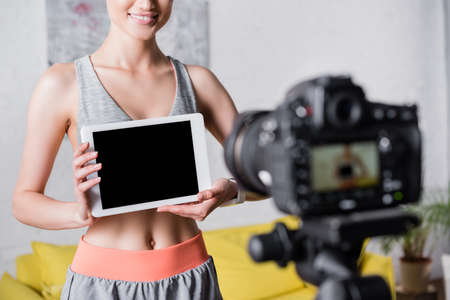 Cropped view of sportswoman holding digital tablet near digital camera at homeの写真素材