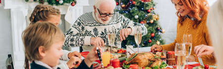 Panoramic shot of family talking and eating thanksgiving dinner, sitting at tableの写真素材