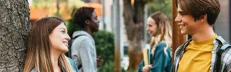 Website header of teenagers talking near tree outdoors