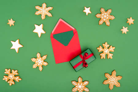 top view of red envelope with card near gift box, baked snowflakes and stars on greenの写真素材