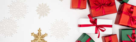panoramic concept of multicolored gift boxes and decorative snowflakes on white background
