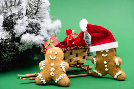 gingerbread men near sled with shopping bag and gift box, and pine branch with decorative snow on...