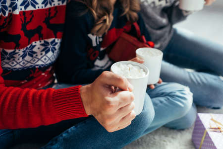 cropped view of man and woman holding cocoa with marshmallows in mugsの写真素材