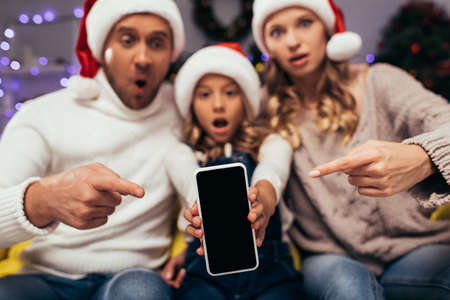 smartphone with blank screen and blurred, shocked family on backgroundの写真素材
