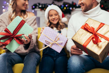 Christmas presents in hands of joyful family on blurred backgroundの写真素材
