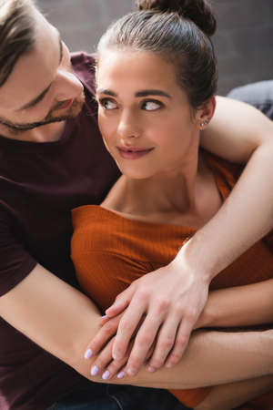 young woman looking at tender boyfriend hugging her from back