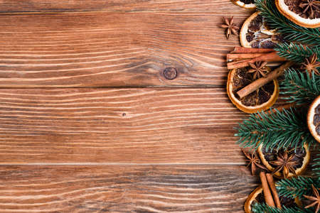 Top view of anise stars, dry orange slices, cinnamon sticks and pine branches on brown wooden backgroundの写真素材
