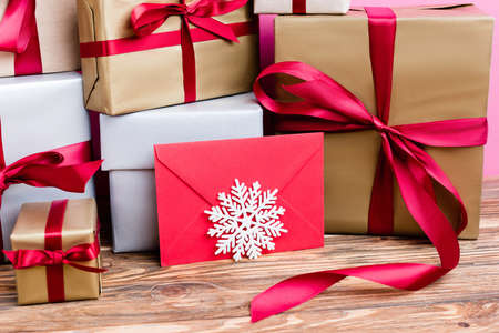 Close up view of gift boxes, red envelope and decorative snowflake on wooden background