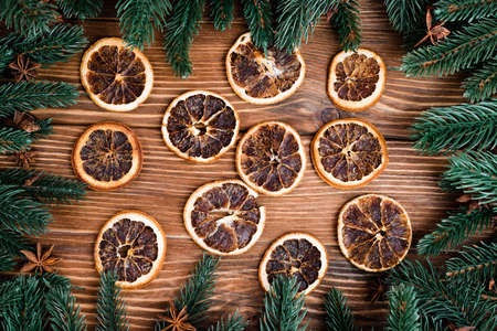 Flat lay with dry orange slices, pine branches and anise stars on brown wooden background, new year conceptの写真素材