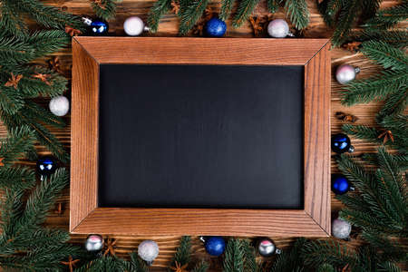 Flat lay with blank chalkboard, baubles, pine branches and anise stars on brown wooden backgroundの写真素材