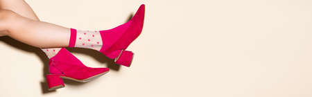 cropped view of female legs in pink retro socks and shoes on beige background, bannerの写真素材