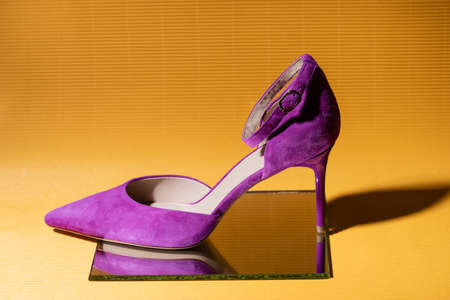 elegant violet suede heeled shoe on mirror on yellow backgroundの写真素材