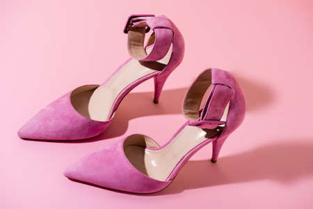 pair of elegant suede heeled shoes on pink background