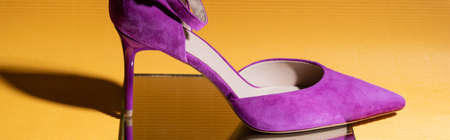 elegant violet suede heeled shoe on mirror on yellow background, bannerの写真素材