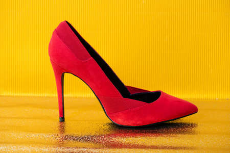 elegant red suede heeled shoe on yellow backgroundの写真素材