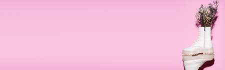 white boots with wildflowers on pink background, banner